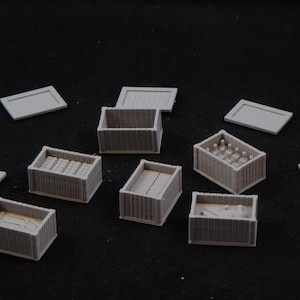 May include: A collection of nine miniature wooden crates, some open and some closed, with various contents, including bottles and other small objects. The crates are made of a light gray material and are arranged on a black surface.