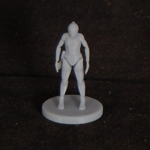 May include: A gray plastic miniature figure of a humanoid robot standing on a round base. The robot has a helmet and is wearing armor.