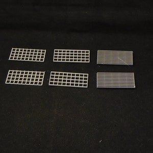 May include: Six small, rectangular metal grilles. Three are made of a fine wire mesh and three are made of a thicker, more spaced out wire mesh.