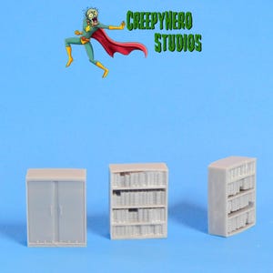 May include: Three miniature gray furniture pieces: a cabinet and two bookshelves. The bookshelves are filled with tiny book replicas. The image also features a cartoon superhero and the text "CREEPYHERO STUDIOS" in green.
