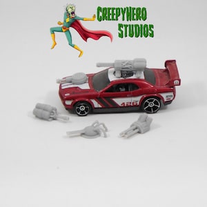 May include: A red and white toy car with a gray gun turret on top and additional gray accessories. The car has the number 426 on the side and black wheels. The image also includes the text "CREEPYHERO STUDIOS".