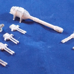 May include: A set of white plastic model ship cannons. The set includes a large cannon and several smaller cannons. The cannons are all in various stages of assembly.