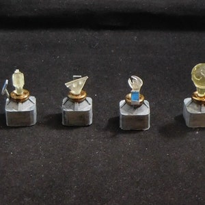 May include: Five small, gray, square containers with different colored, clear plastic toppers. The toppers are shaped like a spaceship, a triangle, a hand, a globe, and a bottle.