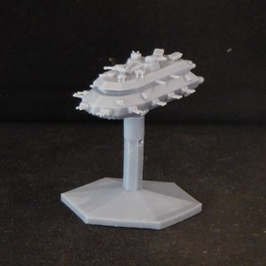 May include: A gray plastic model of a spaceship with multiple turrets and a hexagonal base.