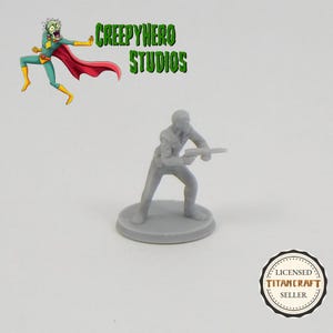 May include: A gray plastic miniature figure of a person holding a gun, standing on a round base. The figure is posed in a shooting stance. The figure is a licensed TitanCraft seller.