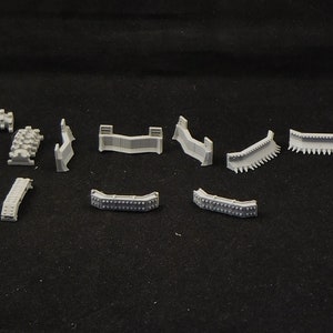 May include: A set of 12 gray plastic track pieces for model building. The pieces are curved and straight, and some have small details like rivets.