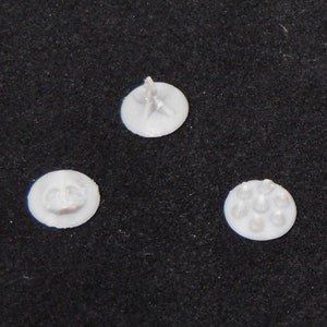 May include: Three white plastic bases with different designs. The first base has a star-shaped design, the second base has a circular design, and the third base has a design with six circles.
