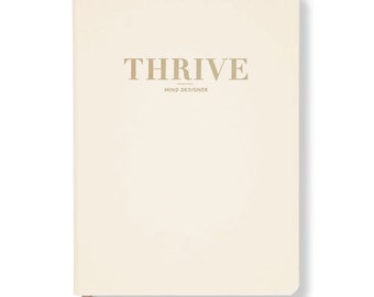 May include: A cream-colored notebook with the word "THRIVE" in gold lettering and the words "MIND DESIGNER" in smaller gold lettering below.