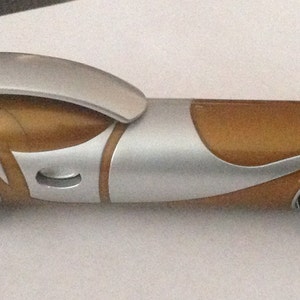 May include: A silver and brown toy car with a futuristic design. The car has a rounded front end and a long, sleek body.