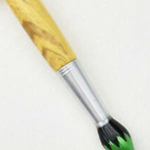 May include: A paintbrush with a light brown wooden handle and a silver ferrule. The bristles are black with green tips. The brush is angled diagonally against a white background.