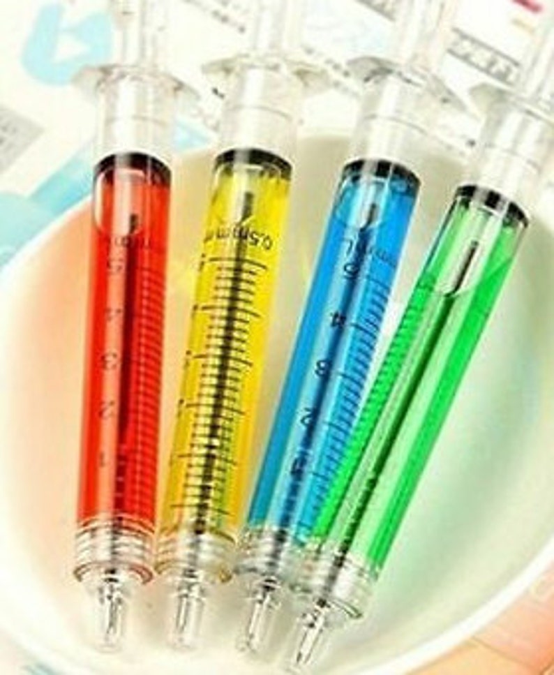 May include: Four plastic syringe pens with colorful ink. The pens are red, yellow, blue, and green.