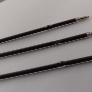 May include: Three black ink refills for a ballpoint pen. The refills are clear plastic tubes with black ink inside. The refills have a silver tip.