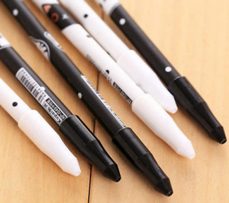May include: A set of five pens featuring a black and white color scheme with polka dot patterns and cat-themed illustrations. Each pen has a contrasting cap and barrel design, with some barrels displaying the text Kupai KP-1049 and a barcode.