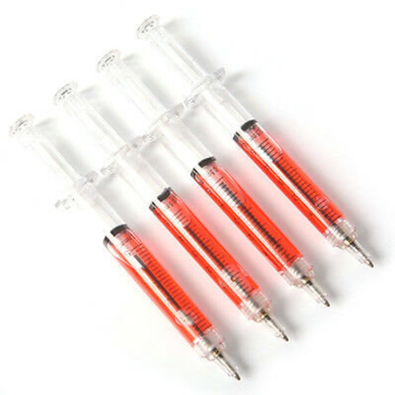 May include: Four clear plastic syringe-shaped pens with red ink. The pens are arranged in a row, with the tips pointing to the right.