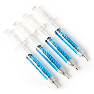 May include: Five clear plastic syringe-shaped pens with blue ink. The pens are arranged in a row, with the tips of the pens pointing to the right.