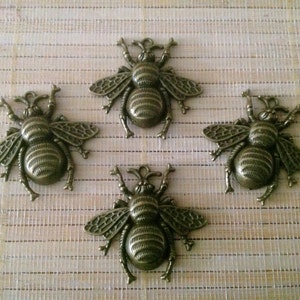 May include: Four antique gold-toned bee charms with detailed wings and bodies. The charms are perfect for jewelry making, scrapbooking, or other craft projects.
