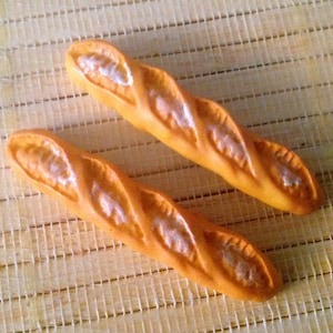 May include: Two long, brown, crusty baguettes on a woven bamboo mat.