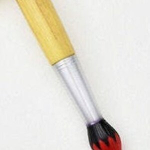 May include: A paintbrush with a light brown wooden handle, a silver ferrule, and a black and red bristle tip. The brush is angled against a white background, showcasing its design and construction.