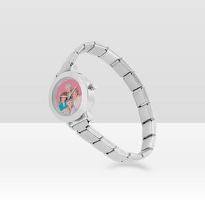May include: A silver wristwatch with a round face displaying a group photograph. The watch features a flexible strap made of rectangular links. The watch face has a pink background.