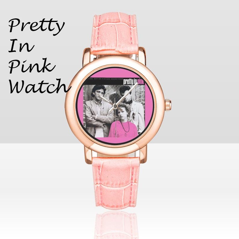 May include: A pink watch with a rose gold case and a pink leather band. The watch face features a black and white image of three people and the words "Pretty in Pink". The watch band is approximately 0.75 inches wide.