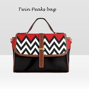 May include: A black handbag with a red and white zigzag pattern on the flap. The bag has a brown leather handle and trim, with the text "Twin Peaks bag" above the bag.