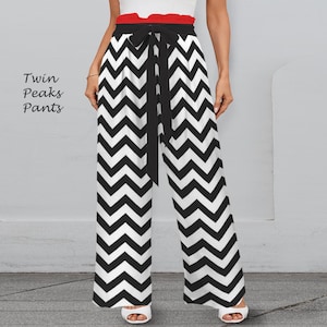 Può includere: Pantaloni a gamba larga con motivo a zig-zag bianco e nero. I pantaloni hanno un cinturino nero in vita e sono abbinati a un top bianco e una fascia in vita rossa. Il testo "Twin Peaks Pants" è sul lato sinistro dell'immagine.