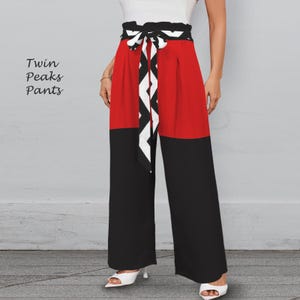 May include: Color-blocked wide-leg pants in red and black with a matching belt featuring a black and white geometric pattern. The pants have a high waist and are paired with white heels. The text "Twin Peaks Pants" is visible on the left.