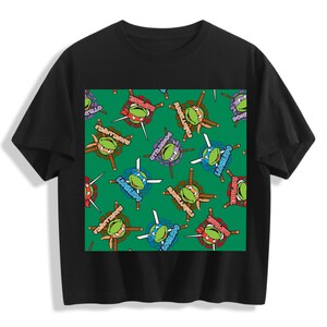 Op de afbeelding: Zwart T-shirt met een herhalend patroon van Teenage Mutant Ninja Turtles op een groene achtergrond. Elke schildpad is afgebeeld met zijn masker kleur en wapen. De tekst "Turtles Vintage style tshirt" staat bovenaan het shirt.
