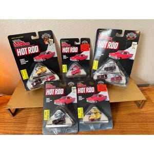 May include: A collection of Racing Champions Hot Rod die-cast model cars on their original packaging. The cards feature red classic cars and the text "Hot Rod". Each package contains a small selection of miniature vehicles in various colors.