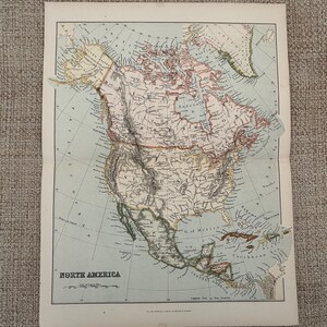 May include: A vintage map of North America, with detailed geographical features. The map is printed on aged paper, with a light blue and beige colour scheme. The title "NORTH AMERICA" is displayed at the bottom of the map.