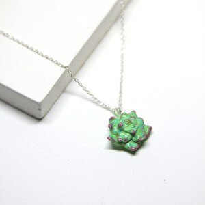 May include: A silver chain necklace with a green and purple succulent pendant.