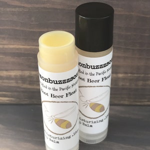 May include: Two white tubes of lip balm with black caps. The labels are white with black text that reads "onbuzzZSO" and "Root Beer Float". The labels also feature a cartoon bee with yellow and brown stripes.