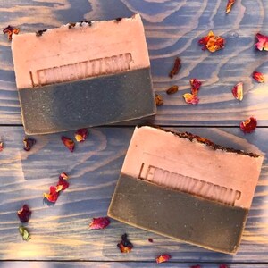 May include: Two bars of handmade soap with a pink and brown color scheme. The soap is labeled "Lemon Butters Soap".