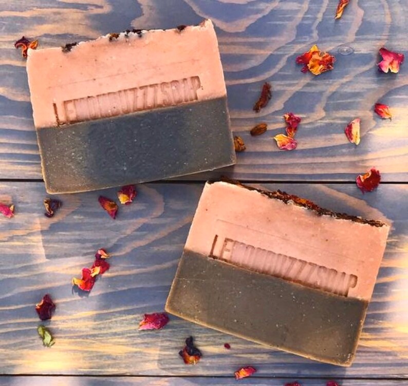 May include: Two bars of handmade soap with a pink and brown color scheme. The soap is labeled "Lemon Butters Soap".
