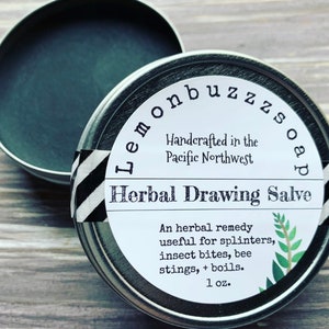 May include: A silver tin with a white label that reads "Lemonbuzz Soap Herbal Drawing Salve". The label also says "Handcrafted in the Pacific Northwest" and "An herbal remedy useful for splinters, insect bites, bee stings, + boils. 1 oz."