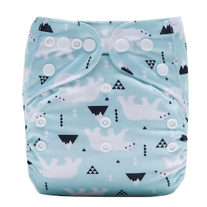 May include: A light blue reusable cloth diaper featuring a repeating pattern of white polar bears, black mountain silhouettes, and small geometric shapes. The diaper includes multiple white plastic snap buttons for adjustable sizing.