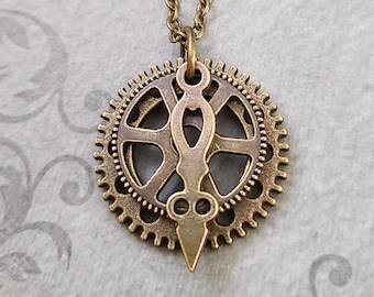 May include: A steampunk-style pendant necklace featuring a bronze-colored gear and a decorative accent. The pendant hangs from a matching chain, creating a vintage aesthetic. The necklace is set against a gray background.