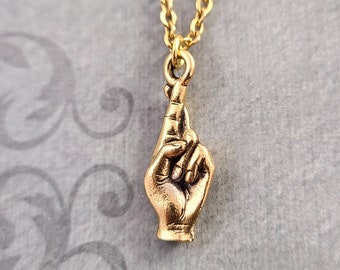 Könnte beinhalten: Goldkette mit einem Anhänger aus zwei ineinander verschlungenen Fingern, symbolisiert ein Versprechen oder Glück.