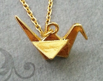 May include: A gold origami crane pendant necklace. The crane is a traditional Japanese symbol of peace and good luck.