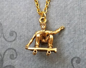 May include: Gold necklace with a pendant of a person skateboarding. The pendant is detailed and shows the person in mid-air with their arms outstretched.