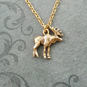 May include: A gold chain necklace with a gold moose pendant. The moose is standing on all four legs and has a detailed design.
