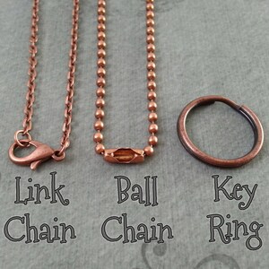 May include: Three copper chains, a link chain, a ball chain, and a key ring. The chains are all the same color and have a shiny finish.