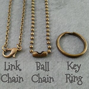 May include: Three different types of chains: a link chain, a ball chain, and a key ring. All are made of a brass-colored metal.