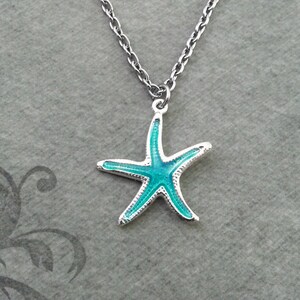 May include: A silver necklace with a starfish pendant. The starfish has a bright turquoise centre and silver edges. The chain is a delicate, linked design, suitable for everyday wear.