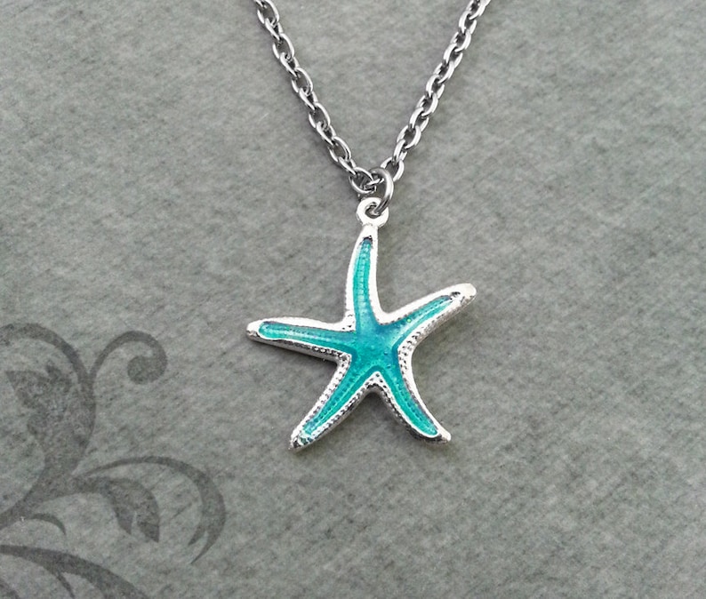May include: A silver necklace with a starfish pendant. The starfish has a bright turquoise centre and silver edges. The chain is a delicate, linked design, suitable for everyday wear.