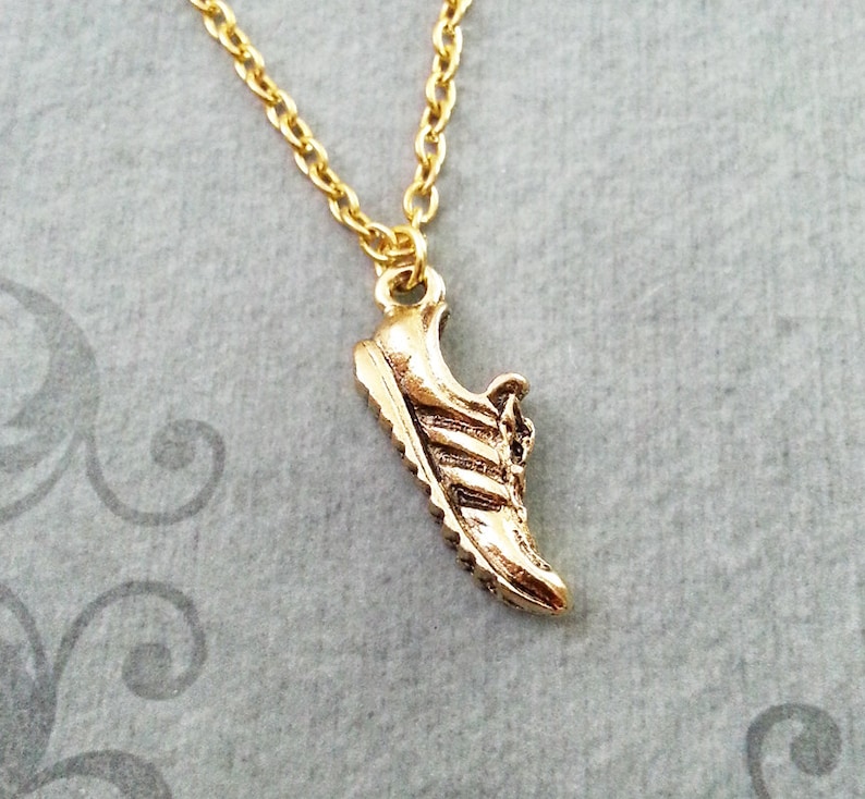 May include: A gold chain necklace with a gold running shoe pendant.