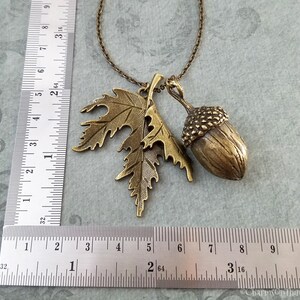 May include: A gold tone necklace with an acorn and leaf charm. The acorn is about 1 inch in diameter and the leaf is about 1.5 inches long.