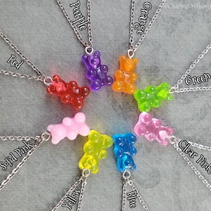 Puede incluir: Un conjunto de ocho collares de ositos de gominola, cada uno de un color diferente: rojo, naranja, amarillo, verde, azul, morado, rosa s&oacute;lido y rosa transparente. Cada collar tiene una cadena plateada y un colgante de osito de gominola.