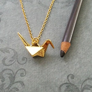 May include: A gold chain necklace with a gold origami crane pendant.