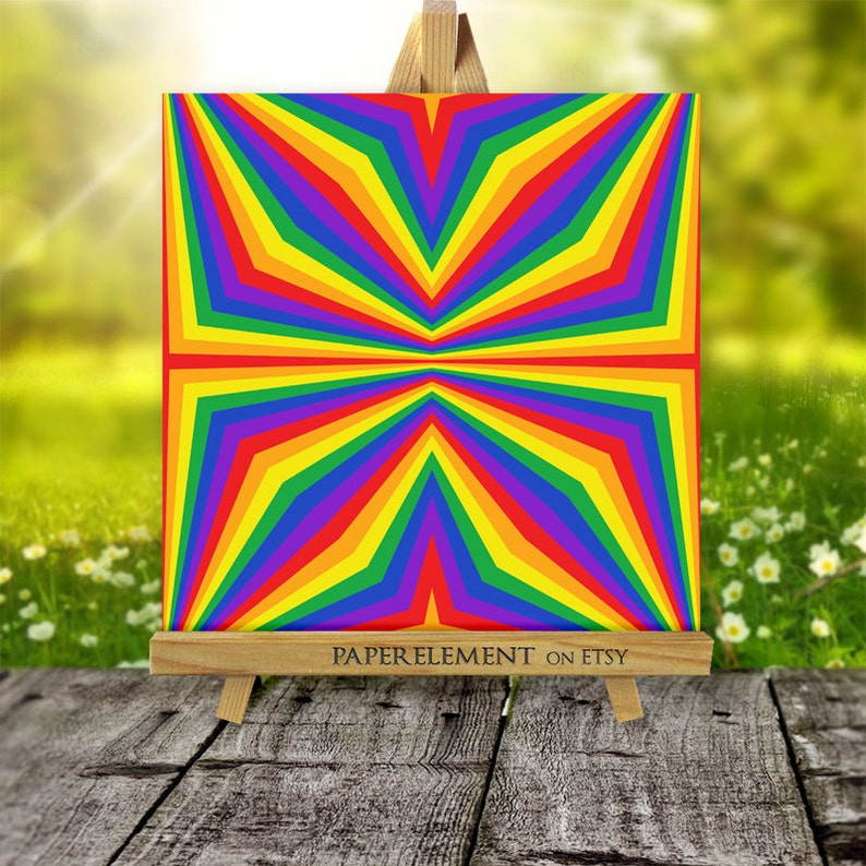 K&ouml;nnte beinhalten: Ein geometrisches Muster in Regenbogenfarben mit einem Sternenausbruch-Design. Das Muster besteht aus abwechselnden Streifen in Rot, Orange, Gelb, Gr&uuml;n, Blau, Indigo und Violett. Das Muster wird auf einem kleinen Holzstaffelei angezeigt.